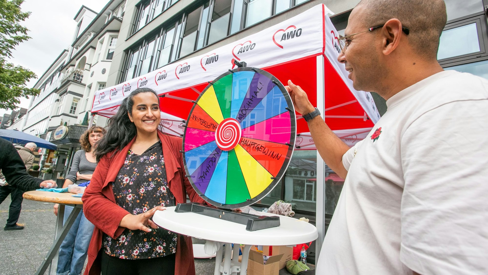 Eine Frau und ein Mann stehen an einem Glücksrad vor einem Pavillon in der Gummersbacher Fußgängerzone.