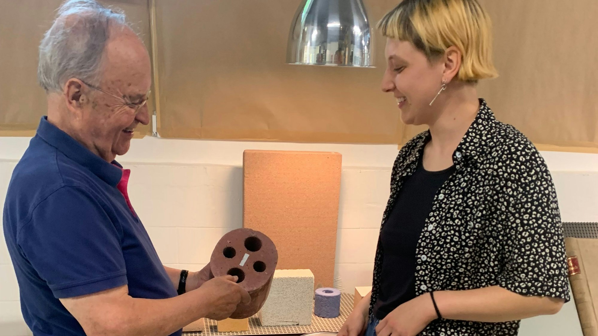 Chemiker Dr. Volker Hofmann erklärt einer Studentin die Funktionsweise eines Plastikteils.