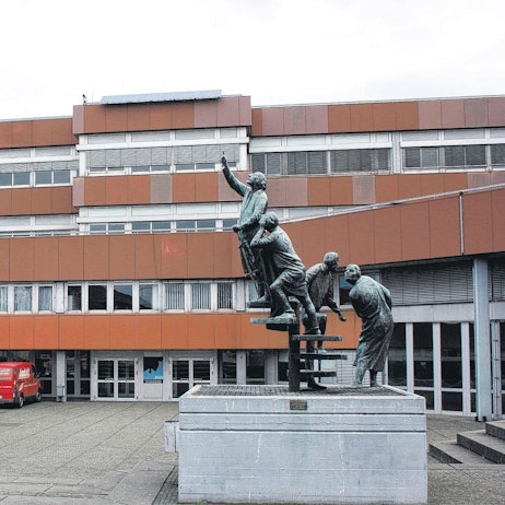 Das Kopernikus-Gymnasium im Schulzentrum Nord in Niederkassel mit einem Denkmal im Vordergrund.