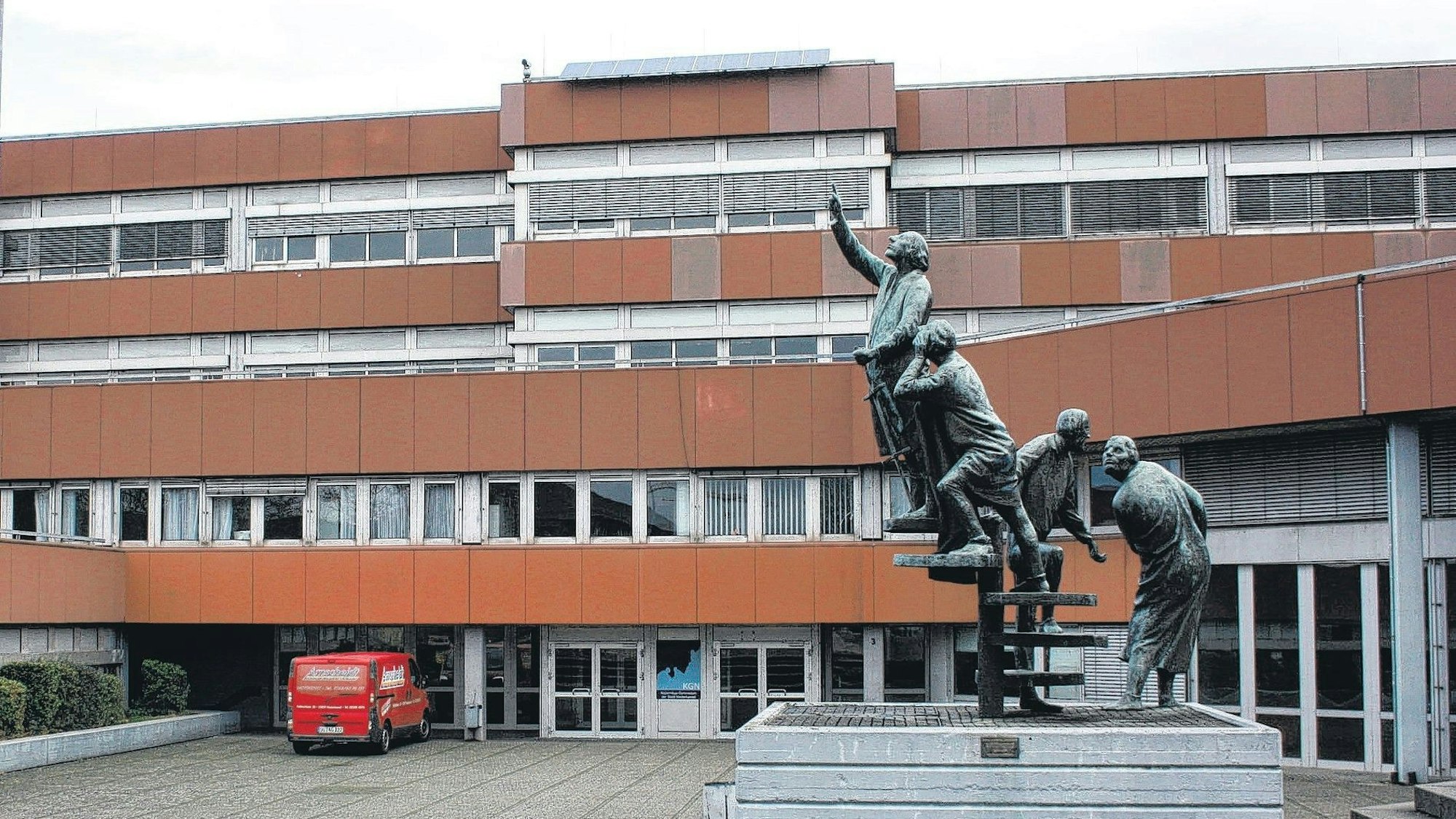 Das Kopernikus-Gymnasium im Schulzentrum Nord in Niederkassel mit einem Denkmal im Vordergrund.