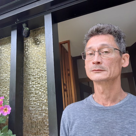 Ein Mann steht neben einer Überwachungskamera an einer Haustür.