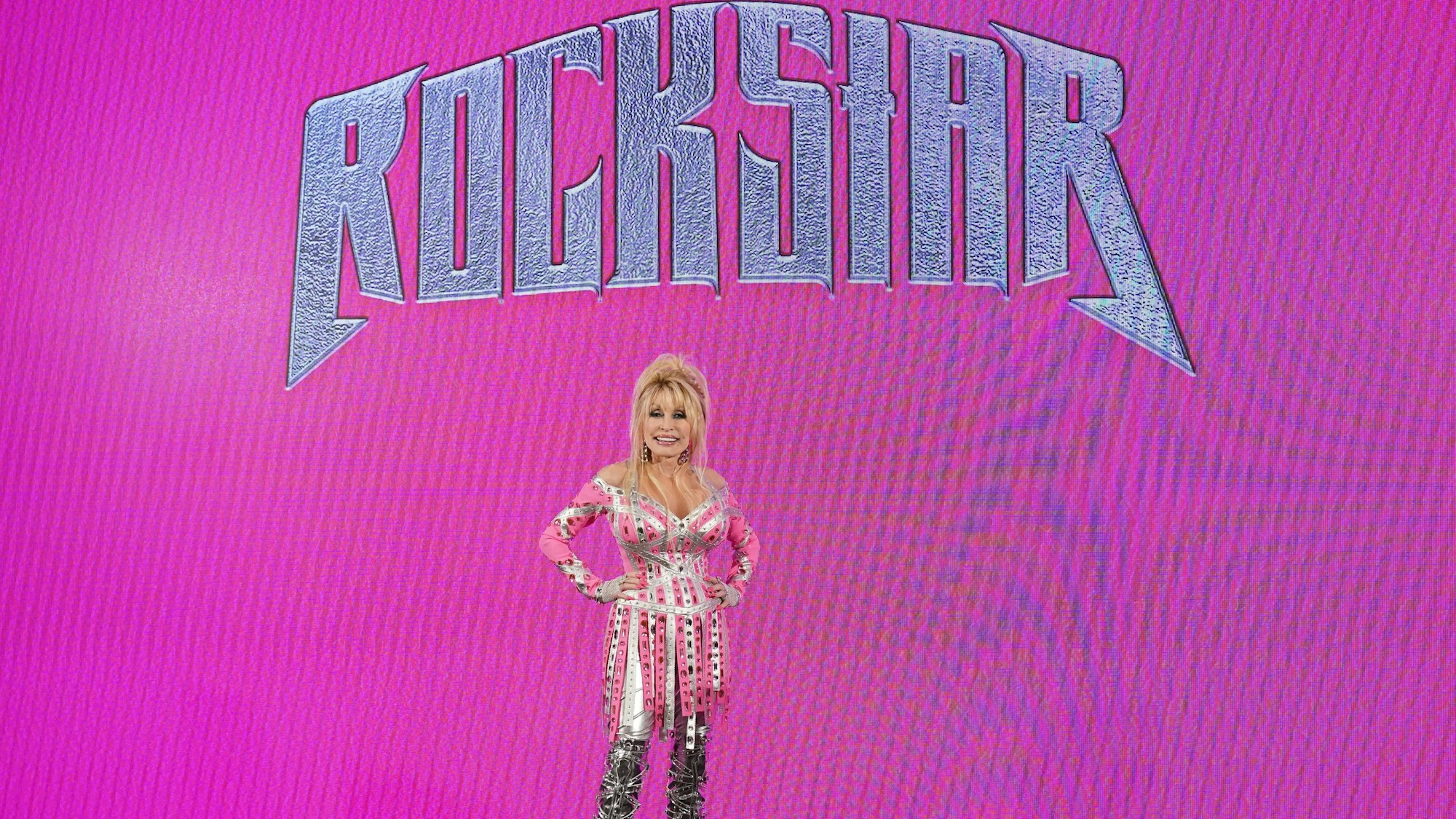 Dolly Parton vor einer Werbewand ihres neuen Albums „Rockstar“.