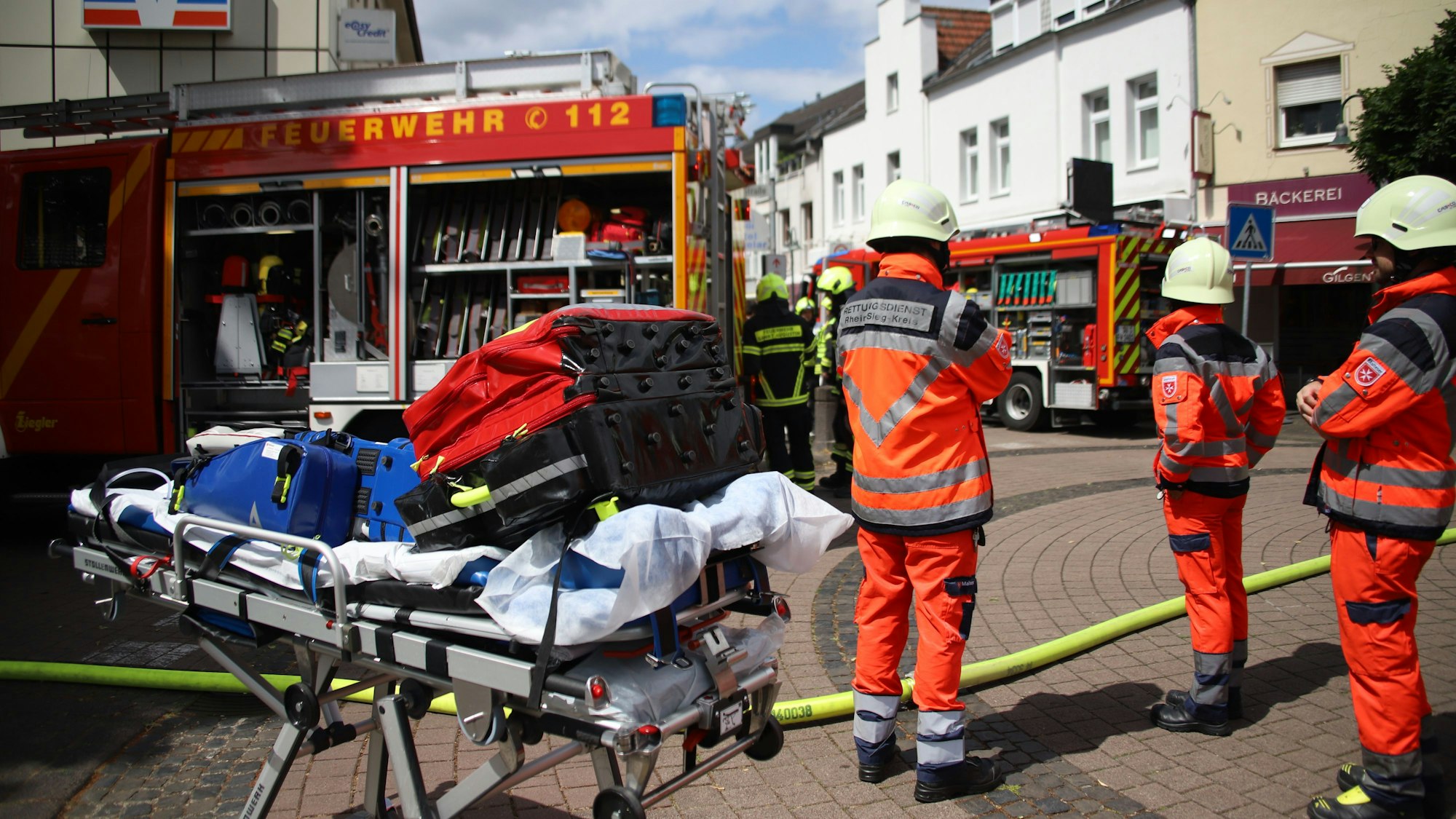 Rettungskräfte stehen vor einem Gebäude auf einer Straße.
