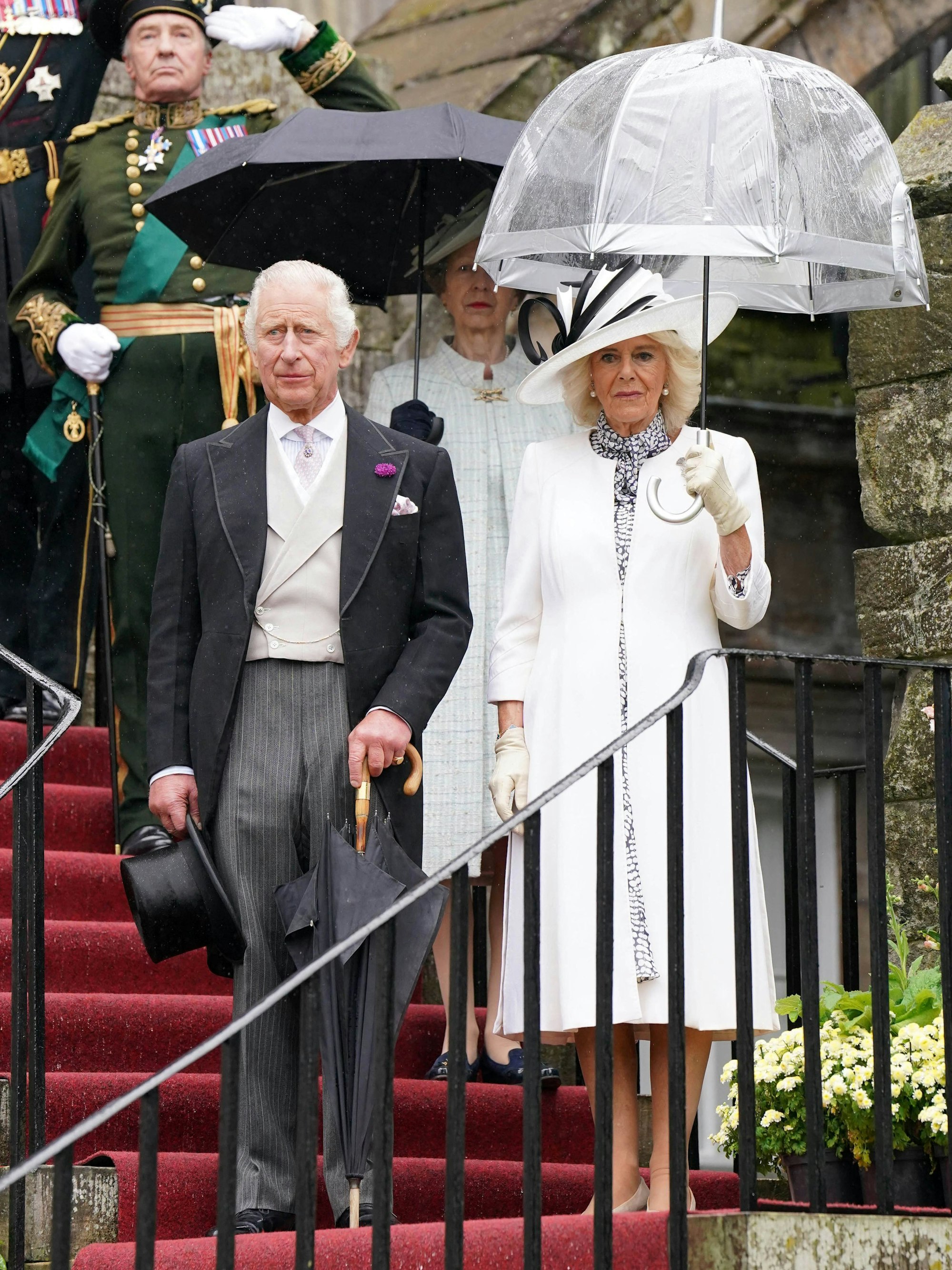 Der britische König Charles III. und die britische Königin Camilla halten während der Nationalhymne inne, als sie am 4. Juli 2023 Gäste zu einer Gartenparty im Palace of Holyroodhouse in Edinburgh empfangen. Im Hintergrund ist auch Prinzessin Anne zu sehen.