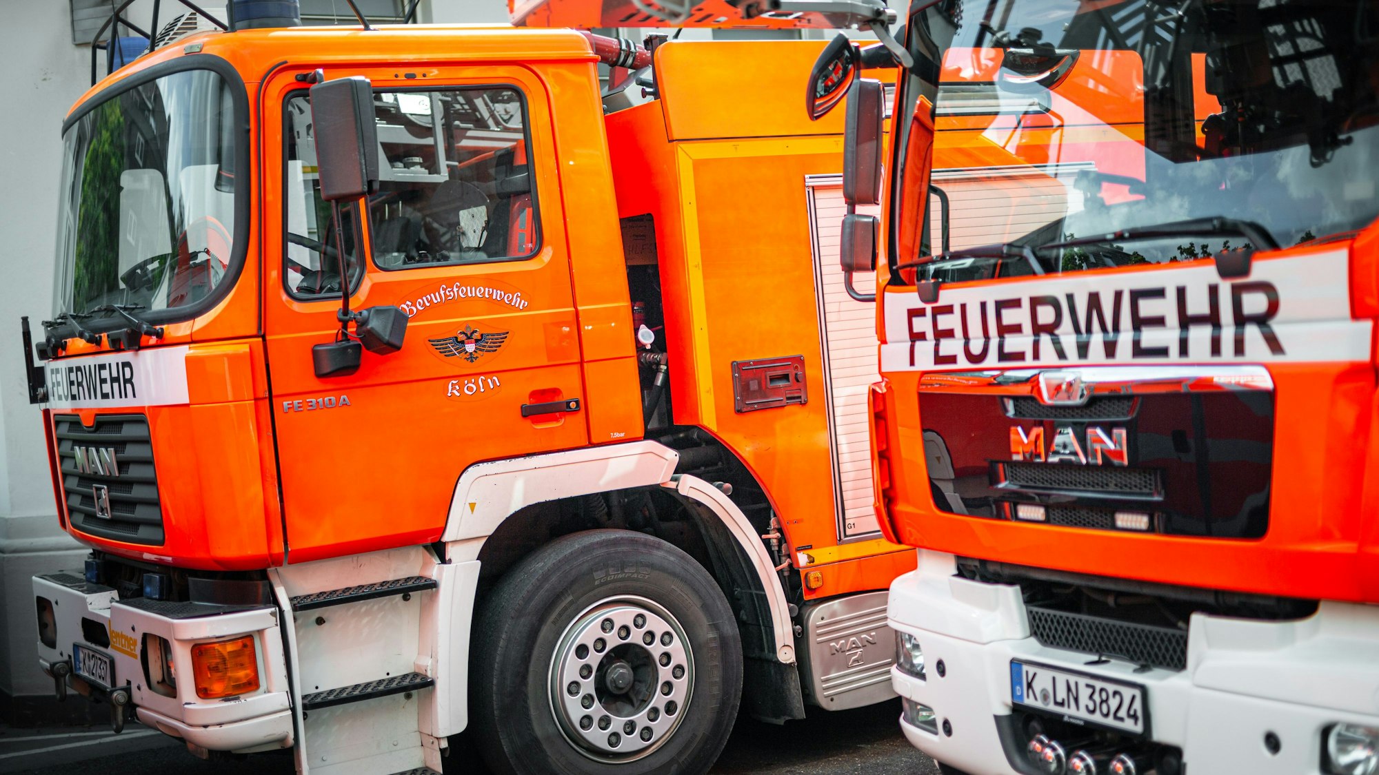 Zwei Fahrzeuge der Berufsfeuerwehr Köln stehen auf dem Hof einer Feuerwache.