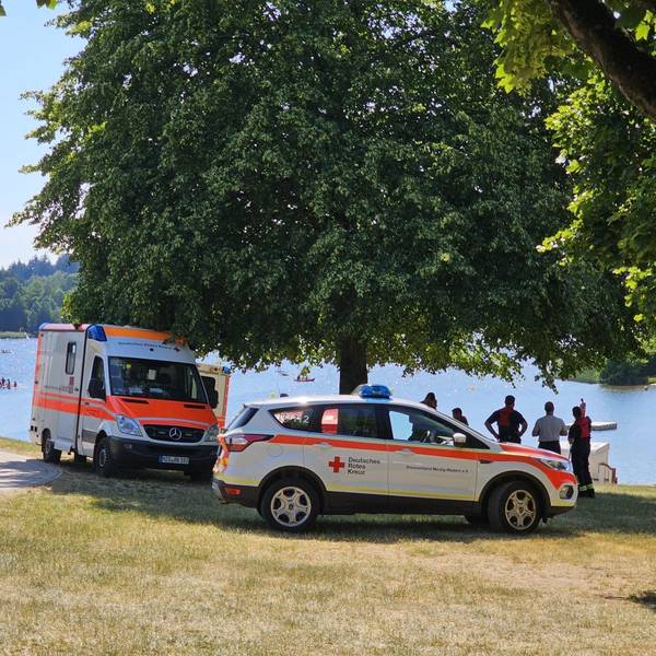 Zwei Krankenwagen stehen an einem Seeufer.