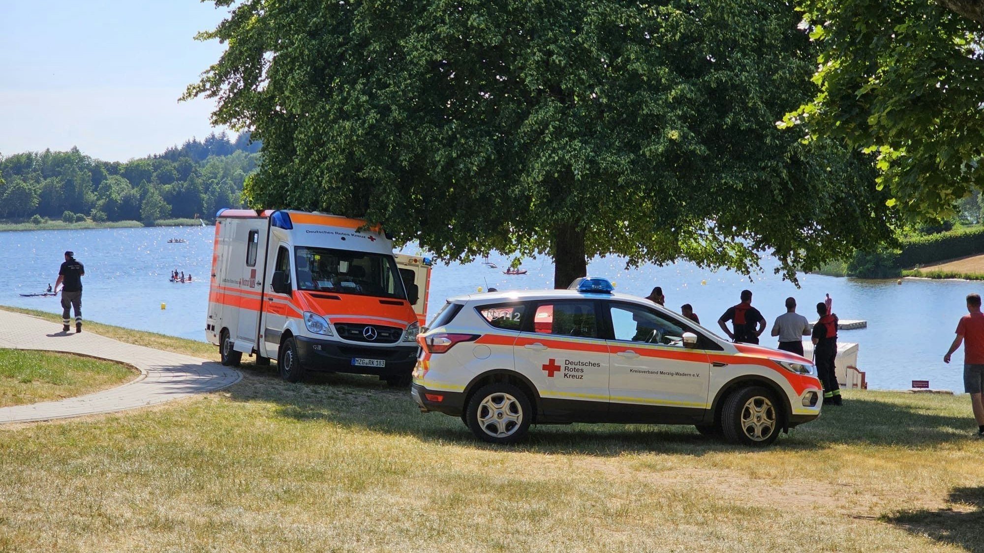 Zwei Krankenwagen stehen an einem Seeufer.
