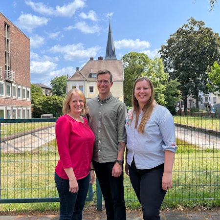 Die evangelischen Geistlichen Judith Manderla, Malte Würzbach und Charlotte Fischer stehen an der Dönhoffstraße in Wiesdorf.