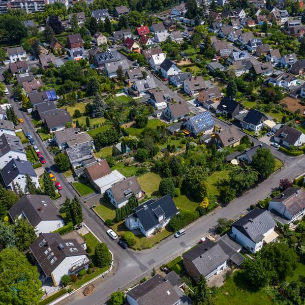 Blick über ein Wohngebiet mit Einfamilienhäusern und mehreren Straßen. In den Gärten stehen zahlreiche Bäume. Das Gebiet hat viele Grünflächen.