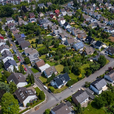 Blick über ein Wohngebiet mit Einfamilienhäusern und mehreren Straßen. In den Gärten stehen zahlreiche Bäume. Das Gebiet hat viele Grünflächen.