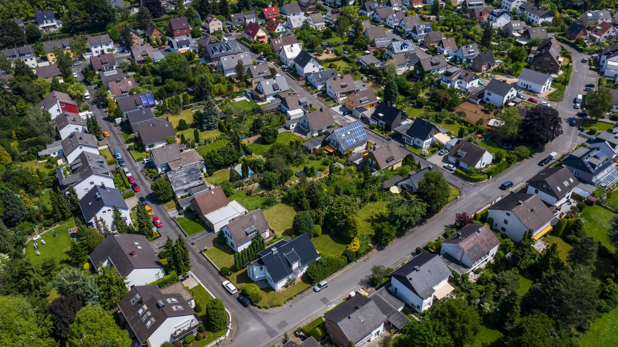 Blick über ein Wohngebiet mit Einfamilienhäusern und mehreren Straßen. In den Gärten stehen zahlreiche Bäume. Das Gebiet hat viele Grünflächen.