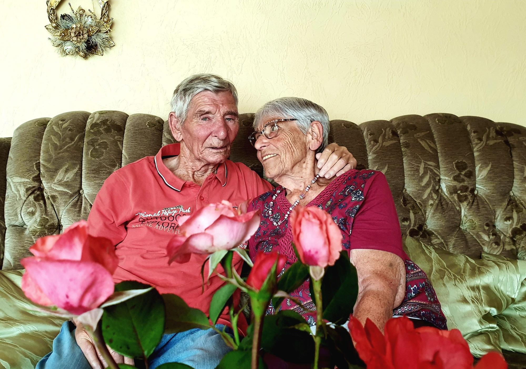 Margret und Bernd Keßenich aus Weilerswist sitzen auf einer Couch und halten sich im Arm. Im Vordergrund sind Rosen.