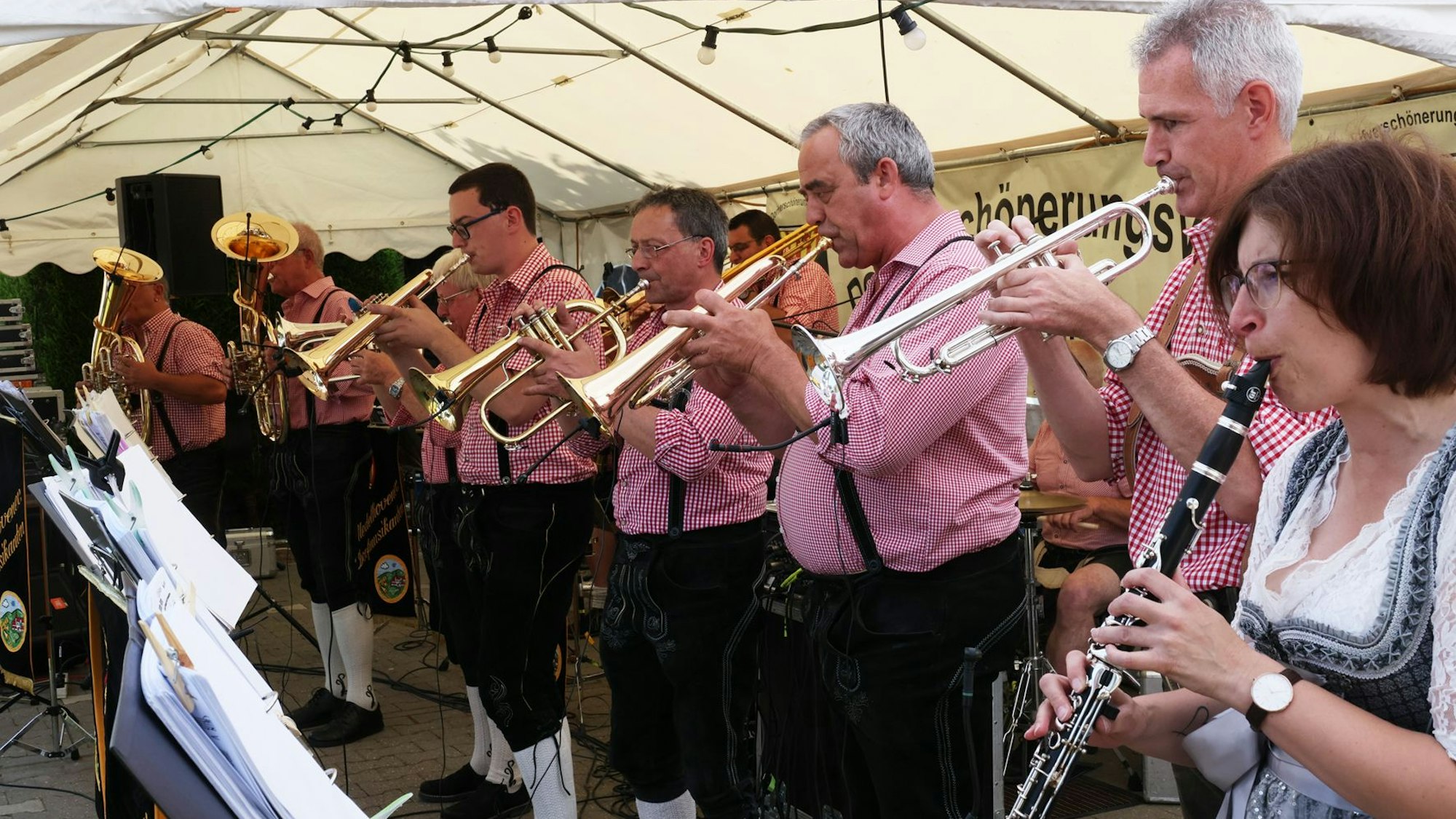 Dorfmusikanten tragen Lederhosen und spielen Blasinstrumente in einem Bierzelt.