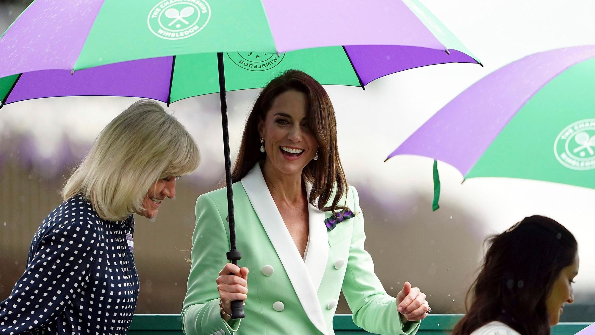 Die britische Prinzessin Kate, Prinzessin von Wales, und die ehemalige Tennisspielerin Debbie Jevans (l) stehen am Dienstag, 4. Juli 2023, während des Erstrundenmatches im Dameneinzel unter Regenschirmen.