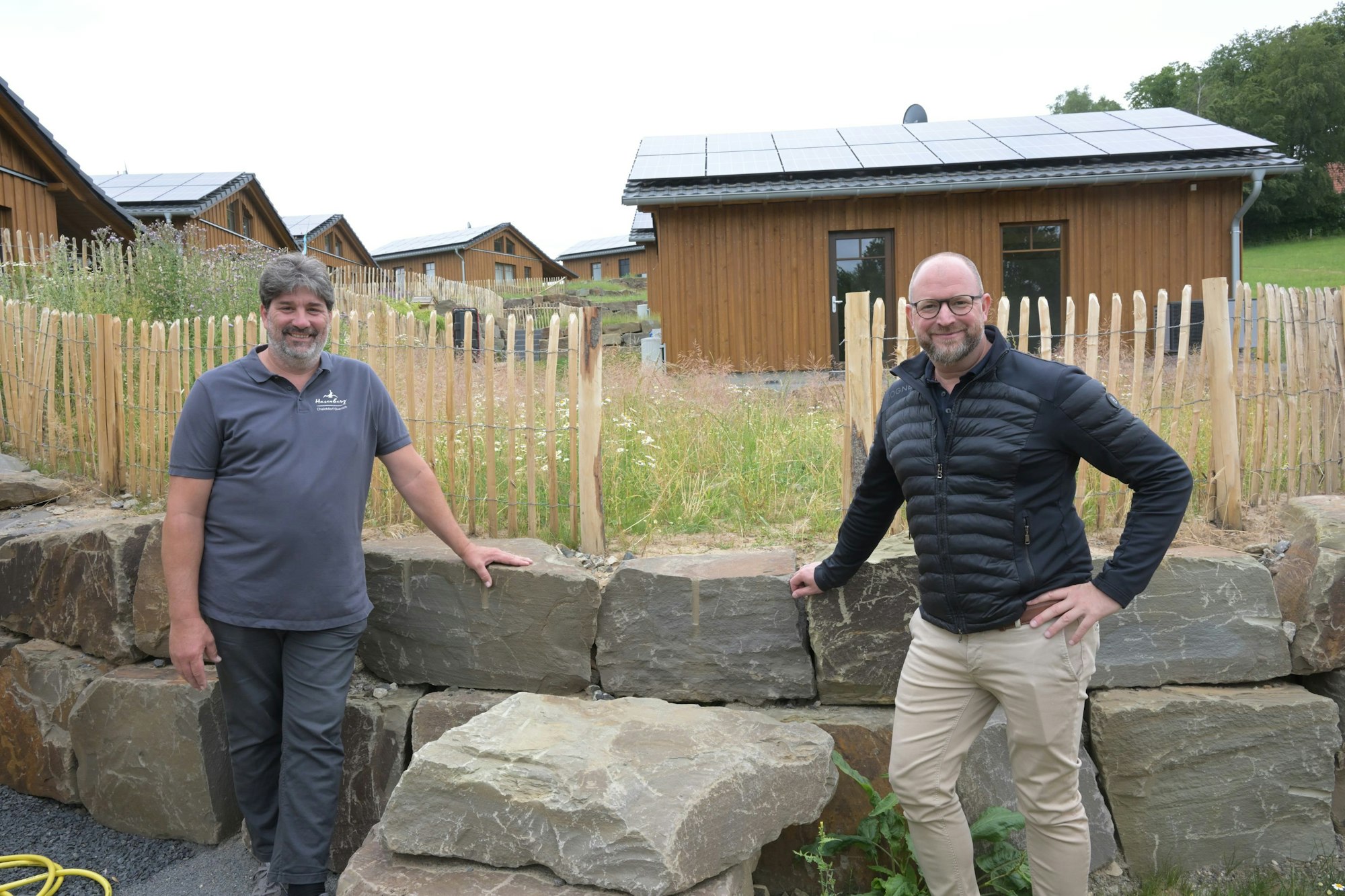 Harald Daunheimer und Matthias Korte stehen vor einer halbhohen Mauer aus großen Begrenzungssteinen.