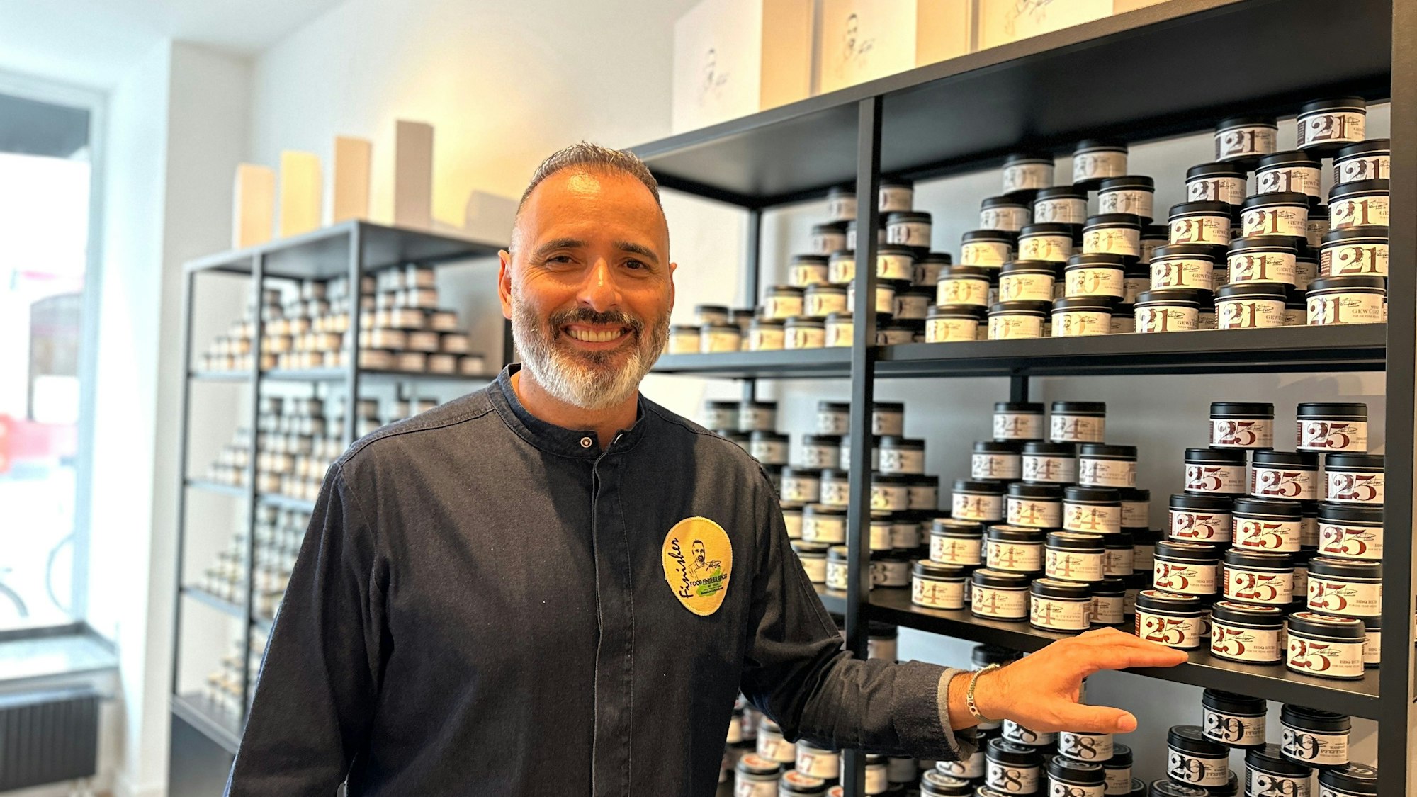 Ein Mann steht vor einem Regal mit Gewürzgläsern.