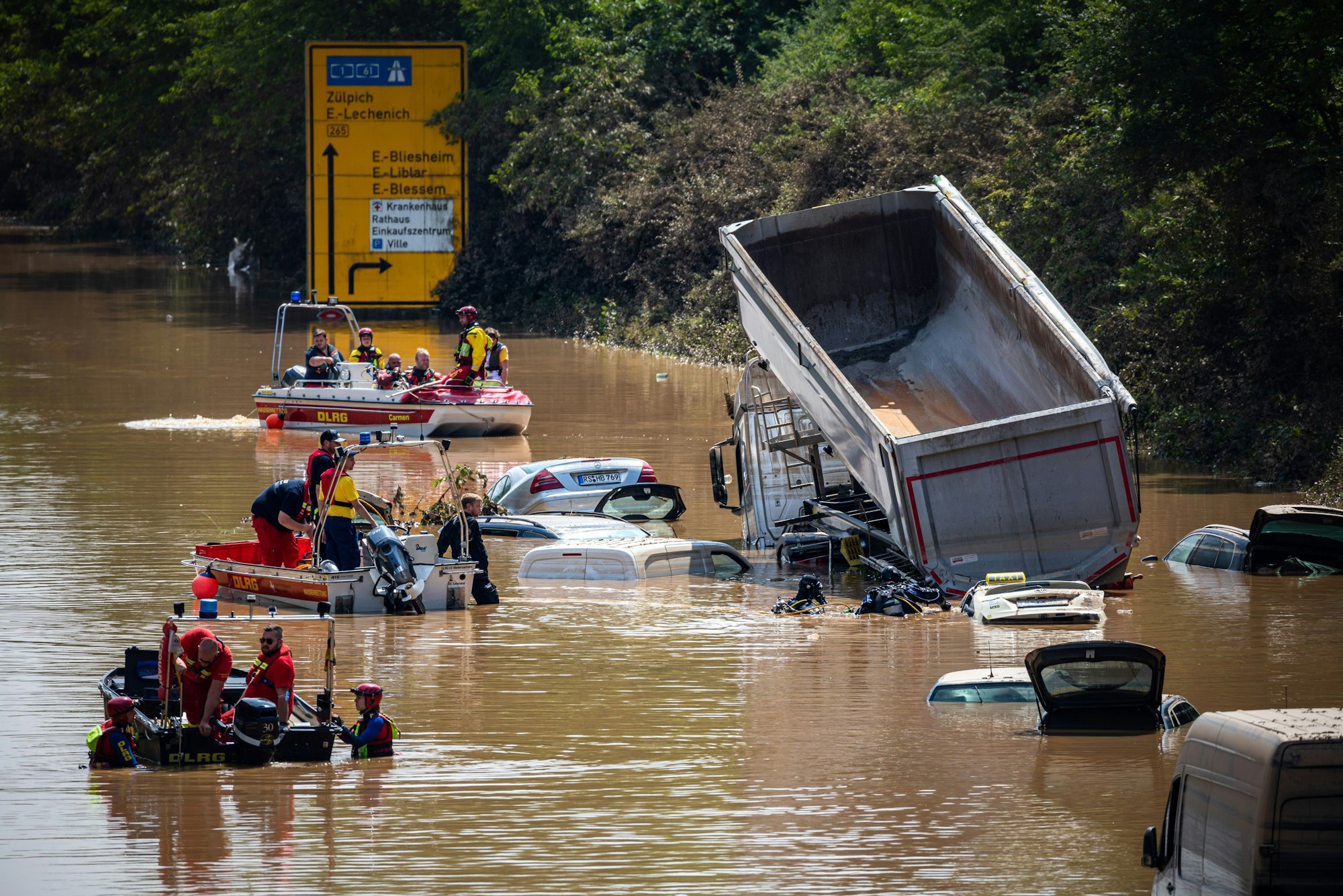 Rettungskräfte bergen zerstörte Autos und Lastkraftwagen, die auf der B265 Luxemburger Straße im Ortsteil Liblar im Hochwasser versunken sind.