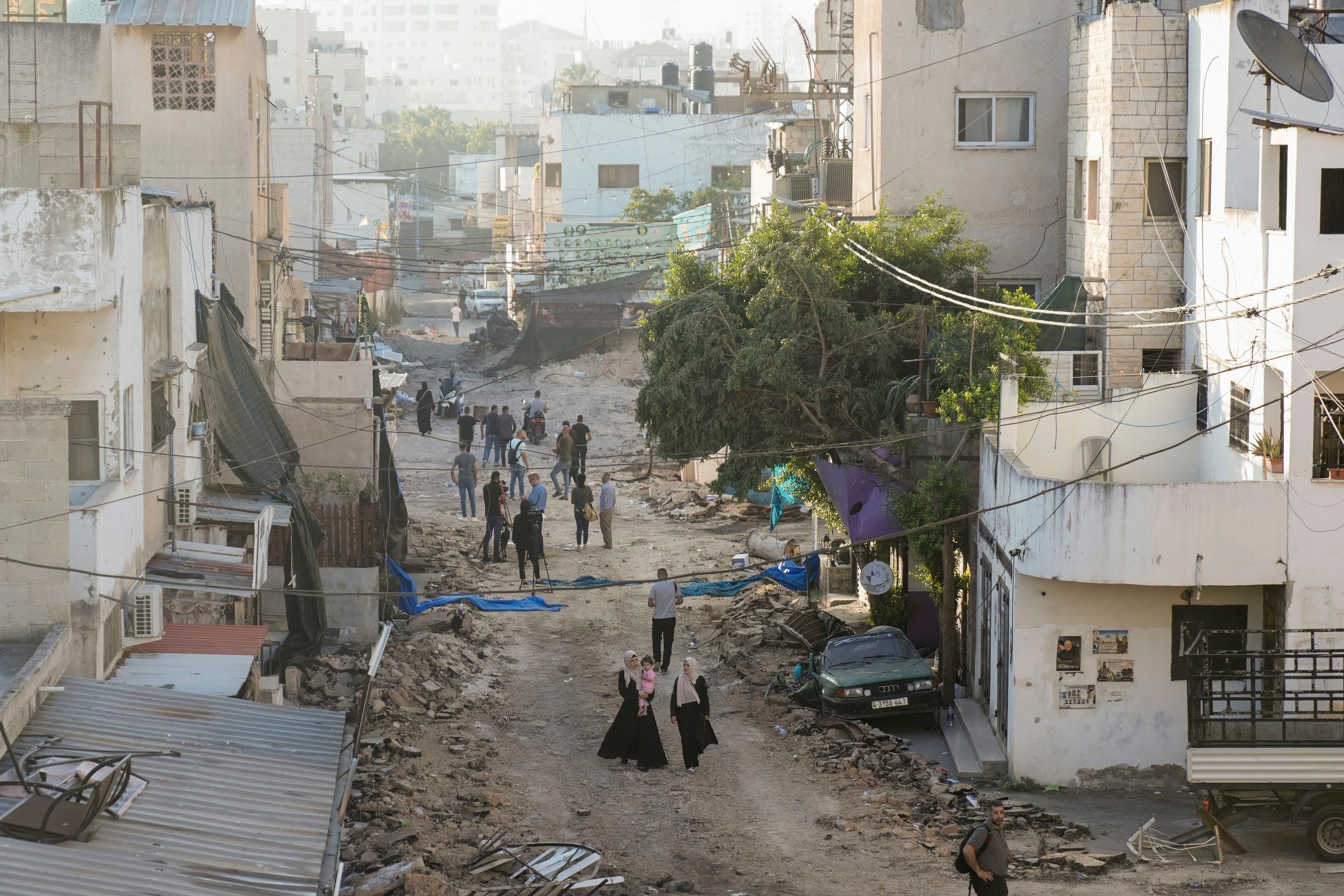 Palästinenser gehen auf einer beschädigten Straße nach Abzug israelischer Truppen.