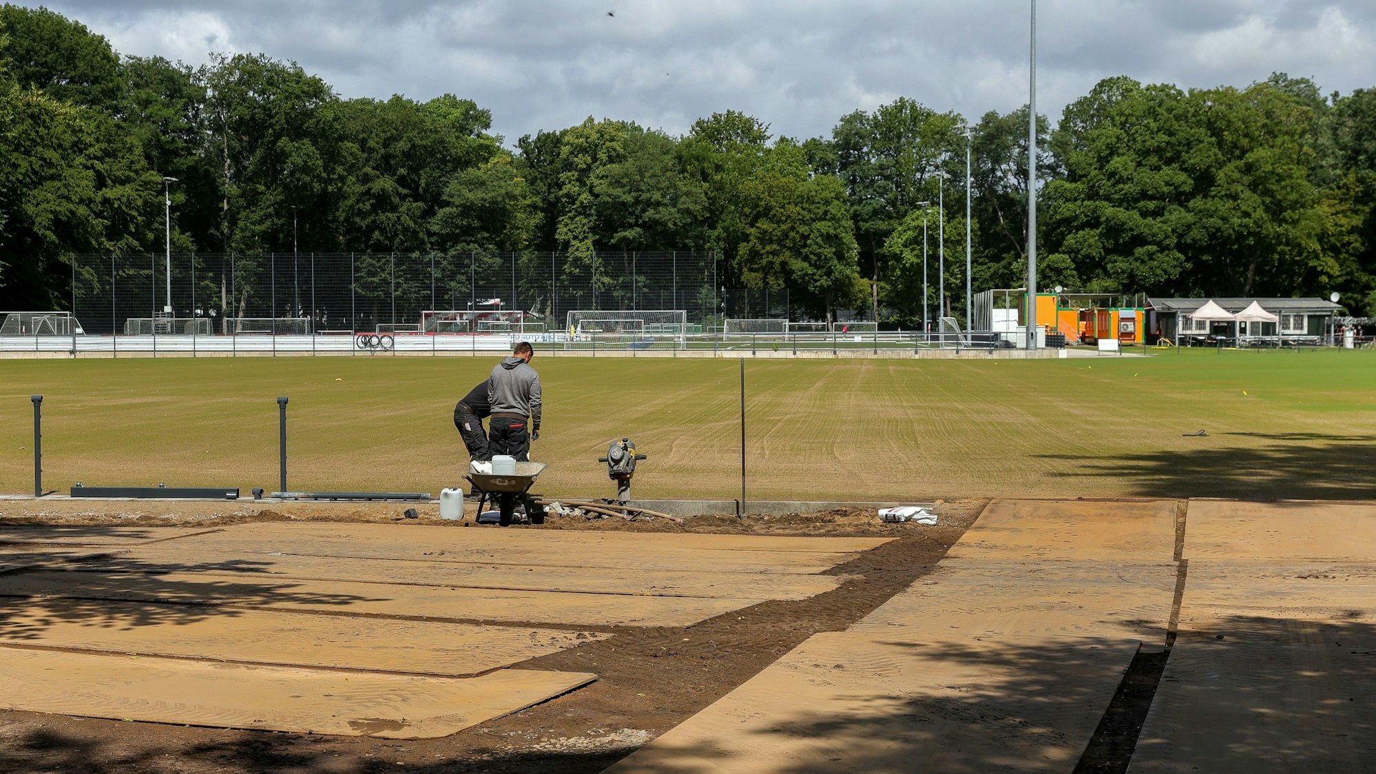 Zu sehen ist ein Fußballplatz des 1. FC Köln am Geißbockheim. Zu sehen sind auch zwei Bauarbeiter.
