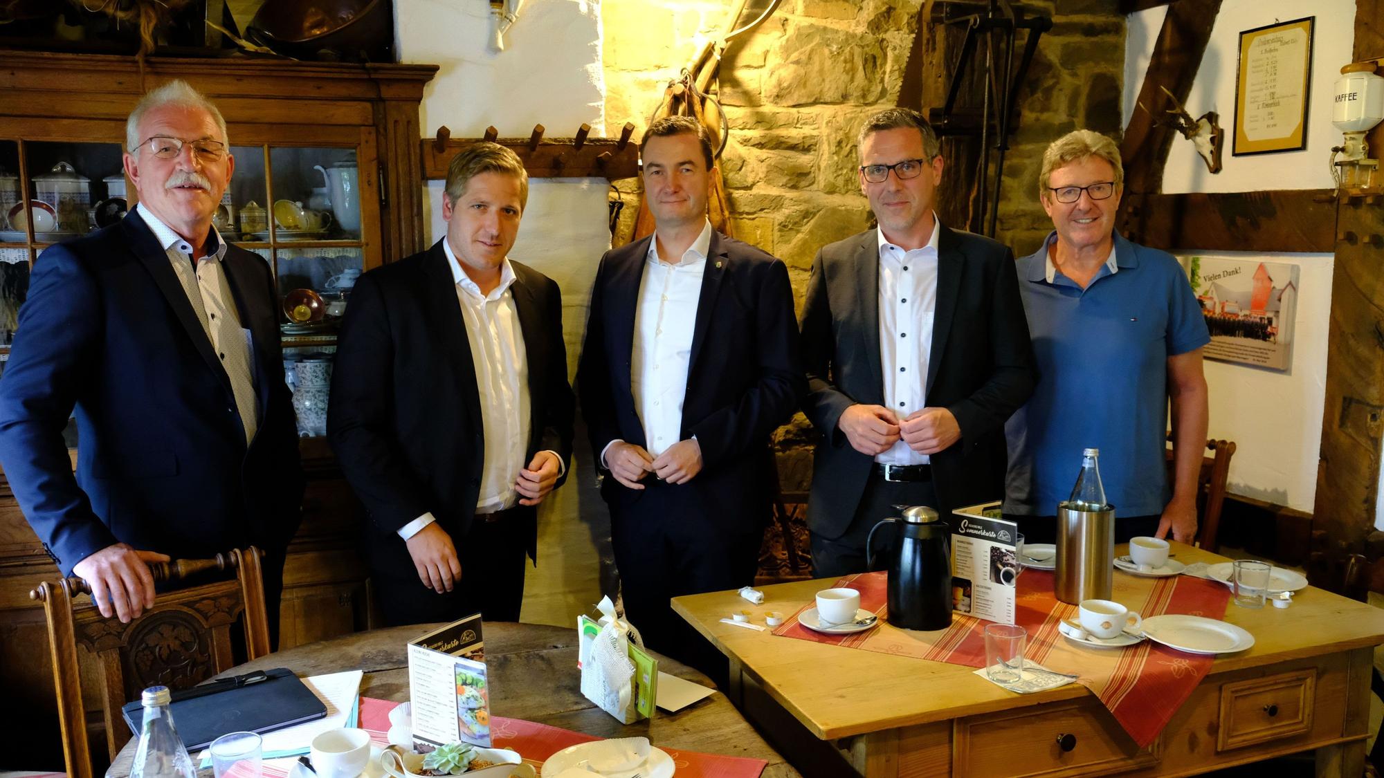 Mehrere Männer stehen in einem Eifeler Fachwerkhaus hinter einem Tisch.