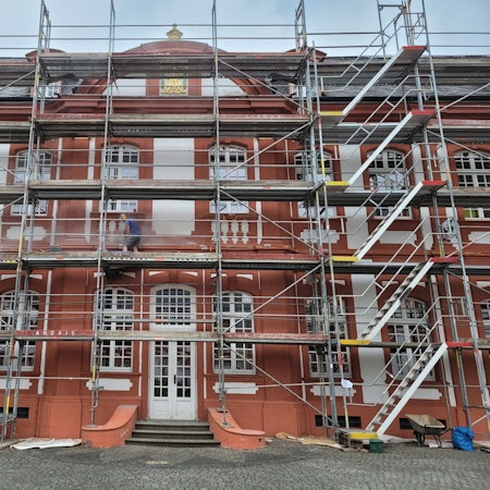 Das Bild zeigt eine Fassade, an der ein Gerüst steht.