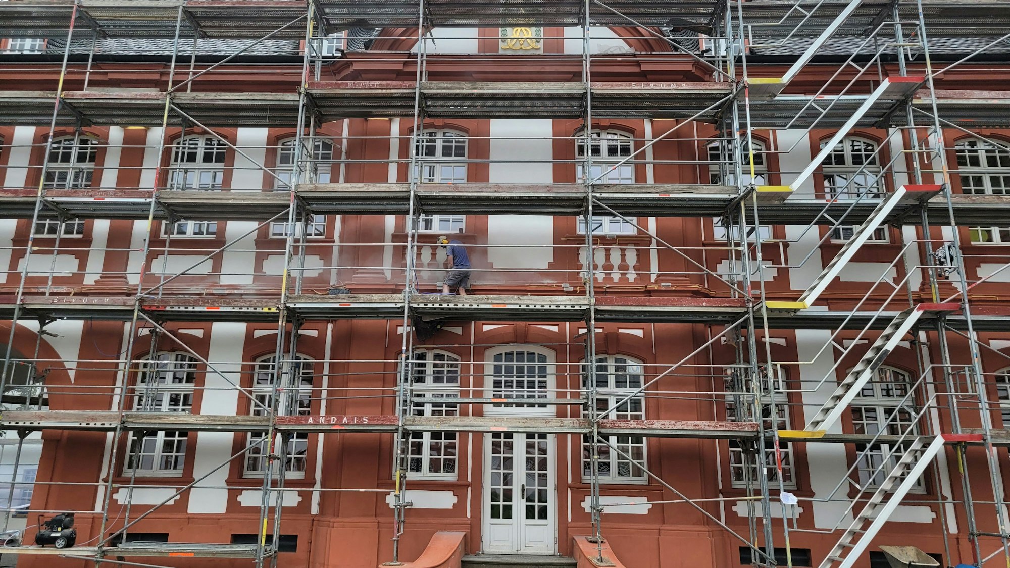 Das Bild zeigt eine Fassade, an der ein Gerüst steht.