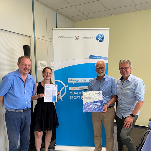 Mitglieder des Kreissportbunds stehen in einer Reihe und halten Exemplare des Bündnis zum Schutz gegen sexualisierte Gewalt in der Hand.