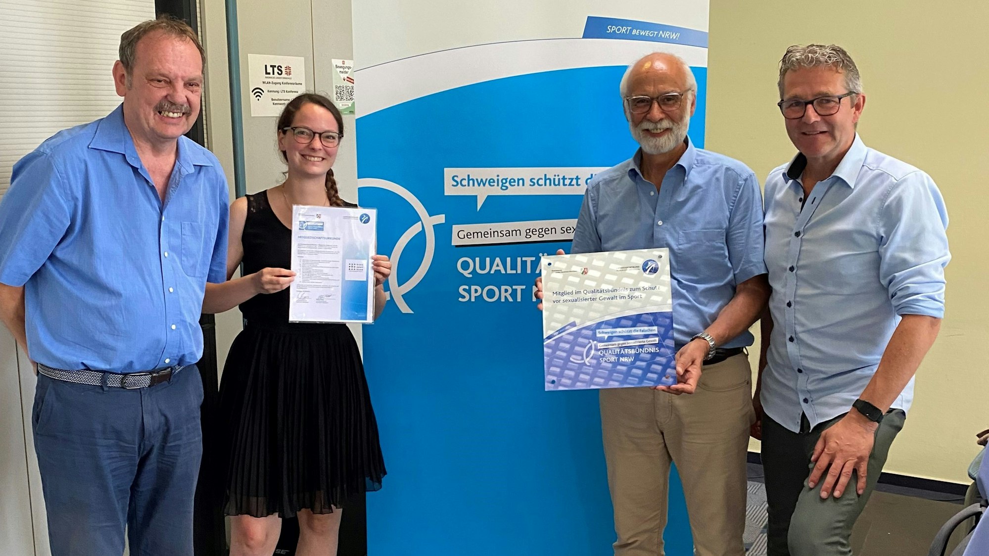 Mitglieder des Kreissportbunds stehen in einer Reihe und halten Exemplare des Bündnis zum Schutz gegen sexualisierte Gewalt in der Hand.