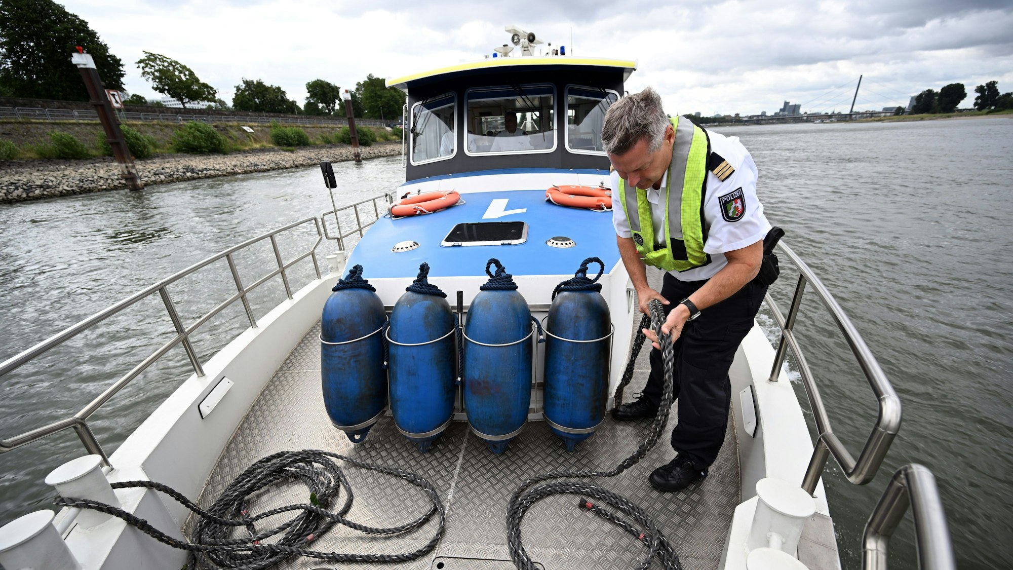 05.07.2023, Nordrhein-Westfalen, Düsseldorf: Hauptkommissar Stefan Wilms schießt beim Wasserschutzboot WSP 1 auf dem Rhein die Leinen auf. Der nordrhein-westfälische Innenminister informierte sich bei dem Besuch über die Arbeit der Wasserschutzpolizei auf dem Rhein. Foto: Federico Gambarini/dpa +++ dpa-Bildfunk +++