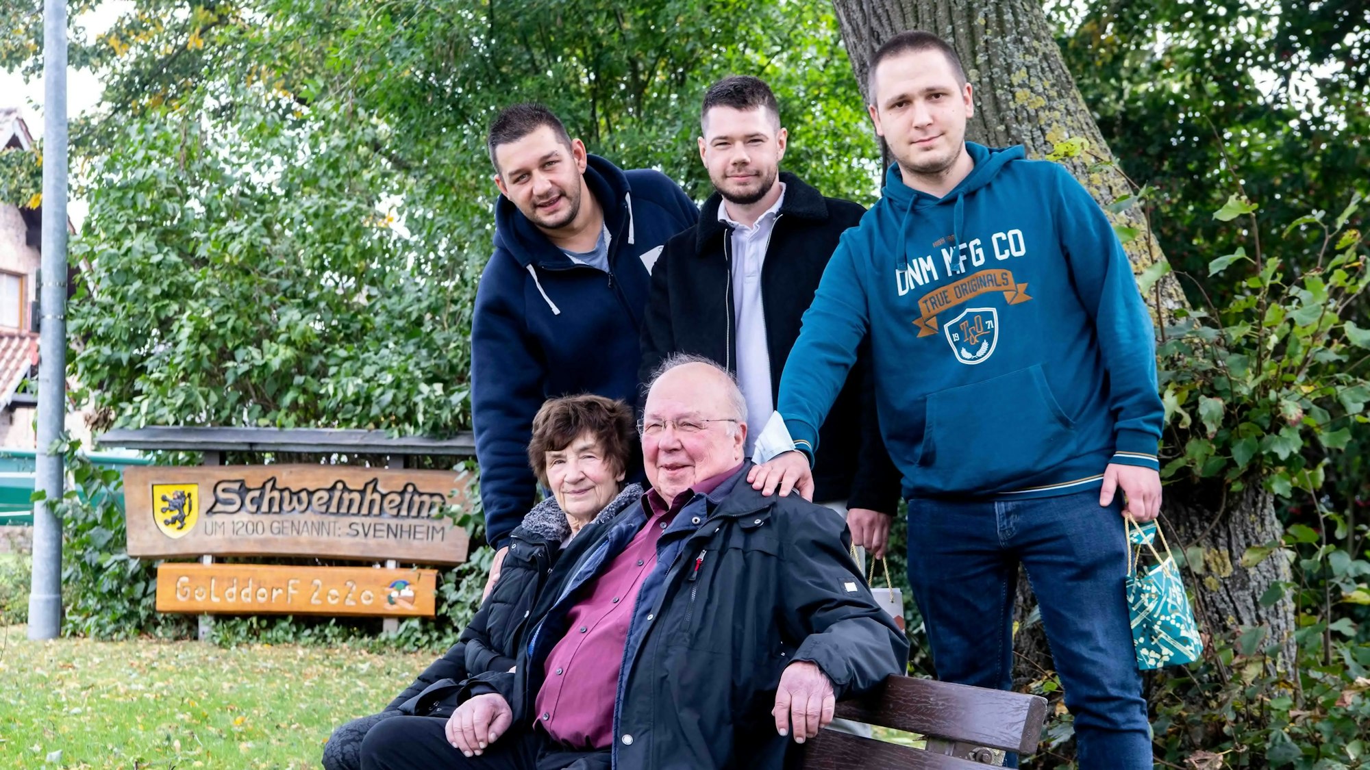 Fluthelfer und Gerettete sitzen und stehen an einer Bank.