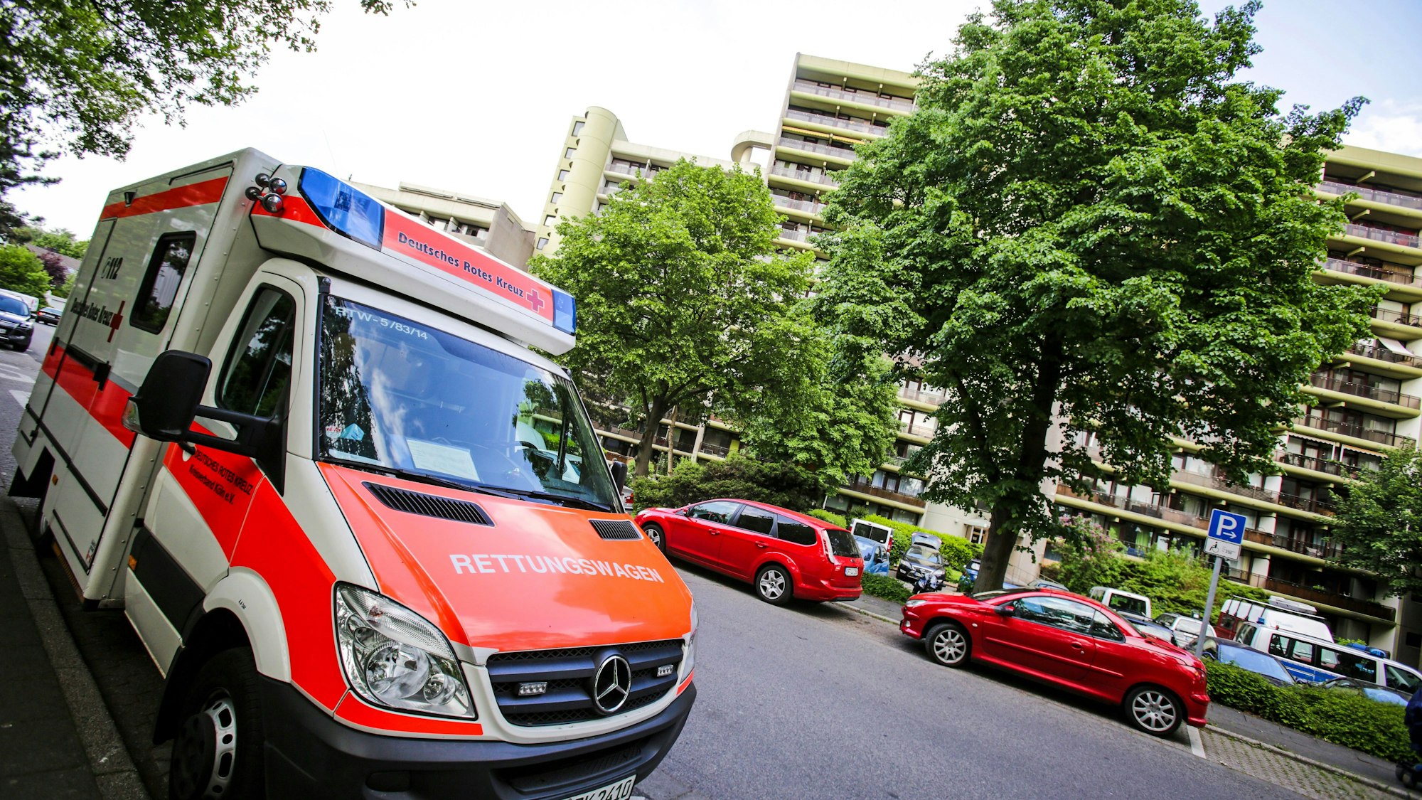 Ein Rettungswagen (RTW) des Deutschen Roten Kreuz (DRK) steht vor einem Wohnhaus am Wiener Weg in Koeln.