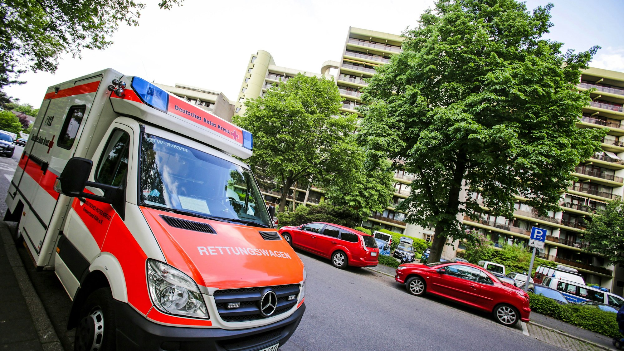 Ein Rettungswagen des Deutschen Roten Kreuz steht vor einem Wohnhaus.