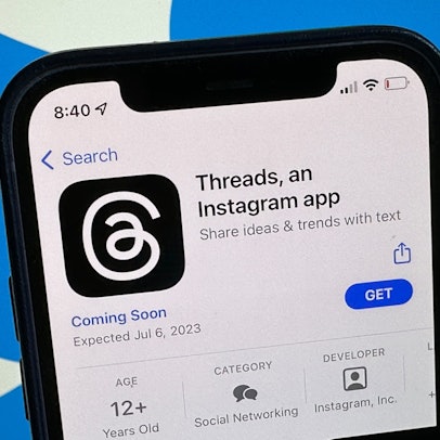Die Ankündigung der Social-Media-App Threads wird im US-amerikanischen App Store von Apple angezeigt. Im Hintergrund ist das Twitter-Logo zu sehen.