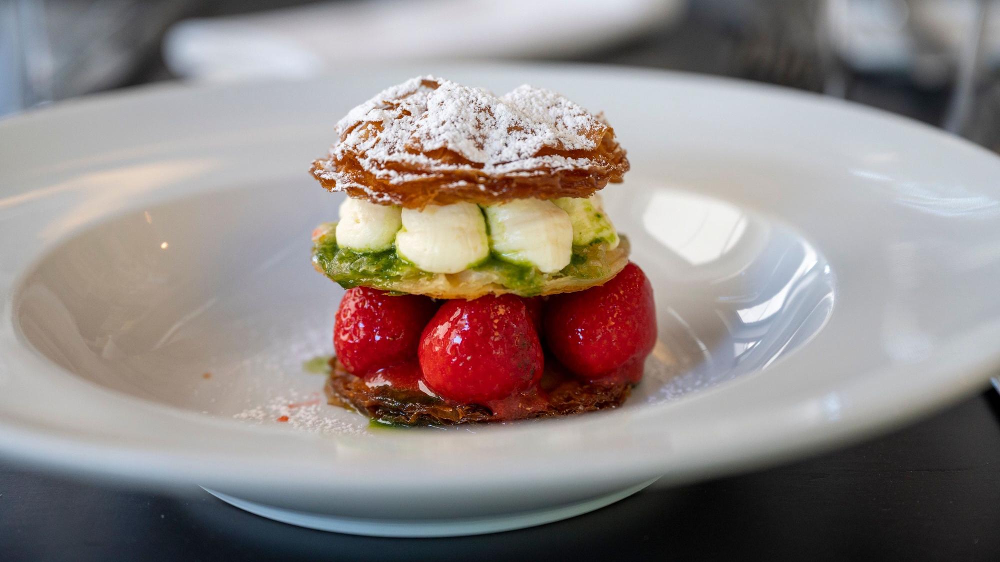 Yufka-Teig-Kreise, Erdbeeren, weiße Schokoladenmousse und Thymiansauce liegen auf einem Teller.