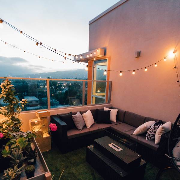 Ein Balkon mit Sofa, Lichterkette Gartenmöbeln.