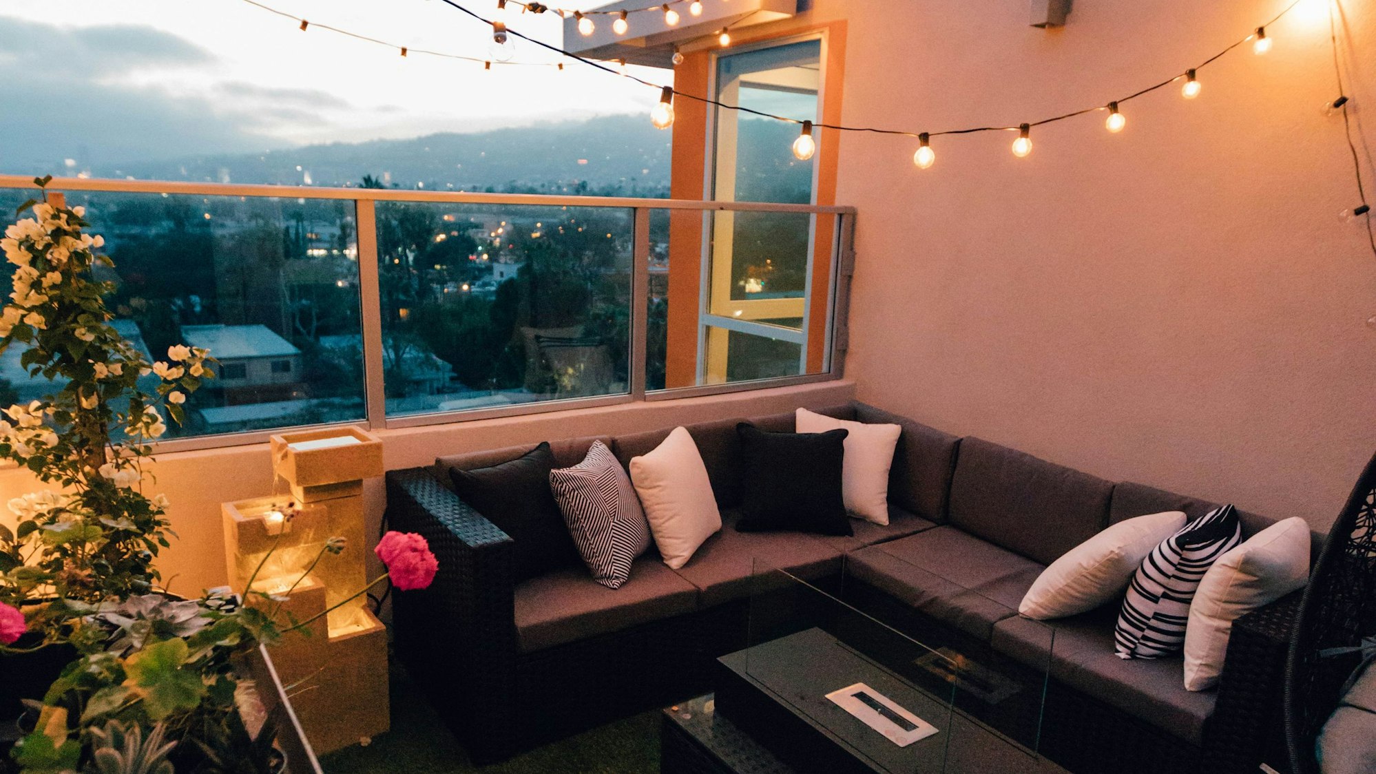 Ein Balkon mit Sofa, Lichterkette Gartenmöbeln.