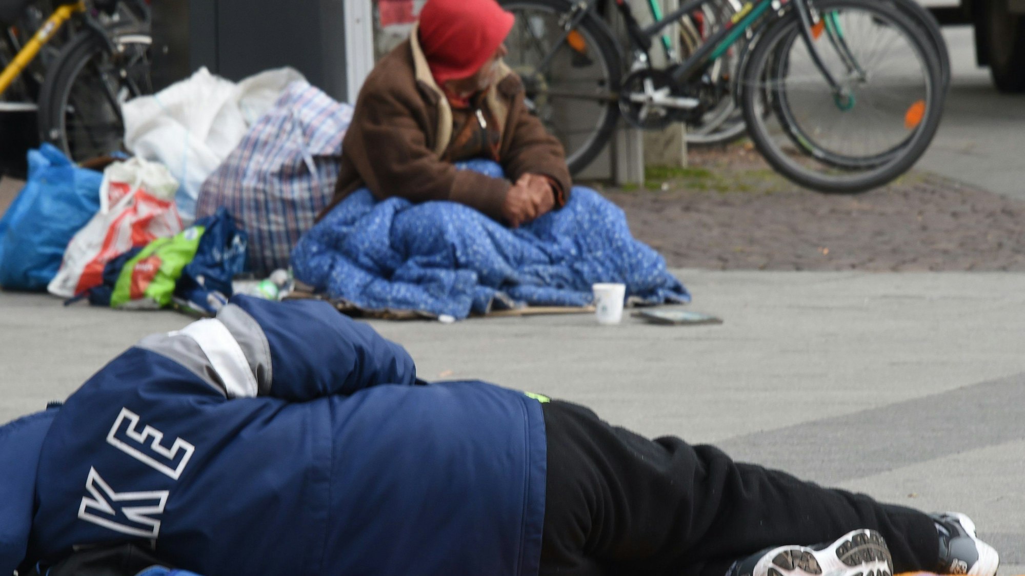 Obdachlose Männer schlafen in einer geschützten Stelle auf der Straße.