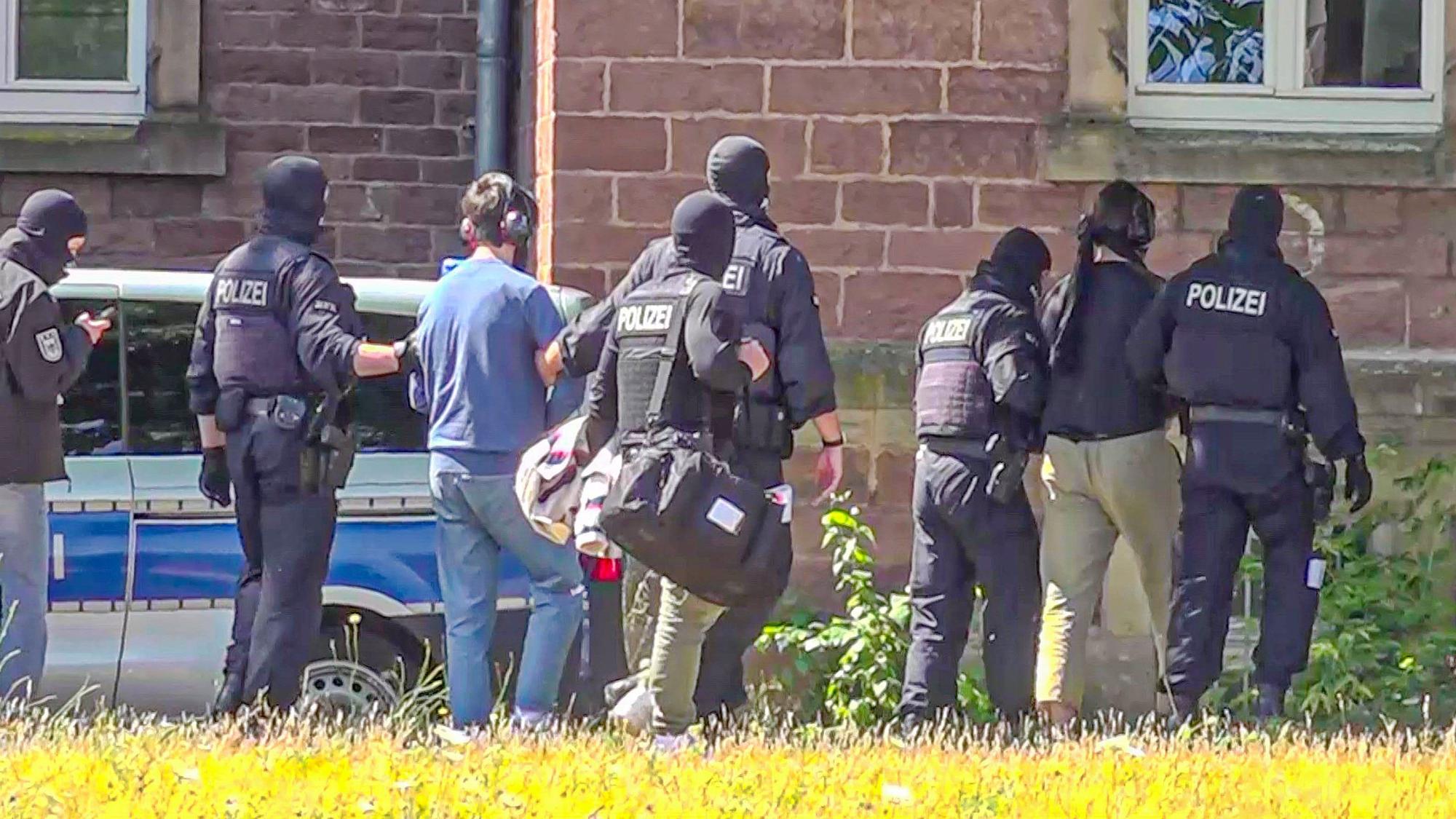 06.07.2023, Baden-Württemberg, Karlsruhe: Zwei der Terrorverdächtigen werden von Polizisten zur Vorführung vor dem Haftrichter gebracht. Die Bundesanwaltschaft hat in Nordrhein-Westfalen eine mutmaßliche islamistische Terrorzelle aufgedeckt und sieben Verdächtige festnehmen lassen. Foto: Waldemar Gess/EinsatzReport24/dpa +++ dpa-Bildfunk +++