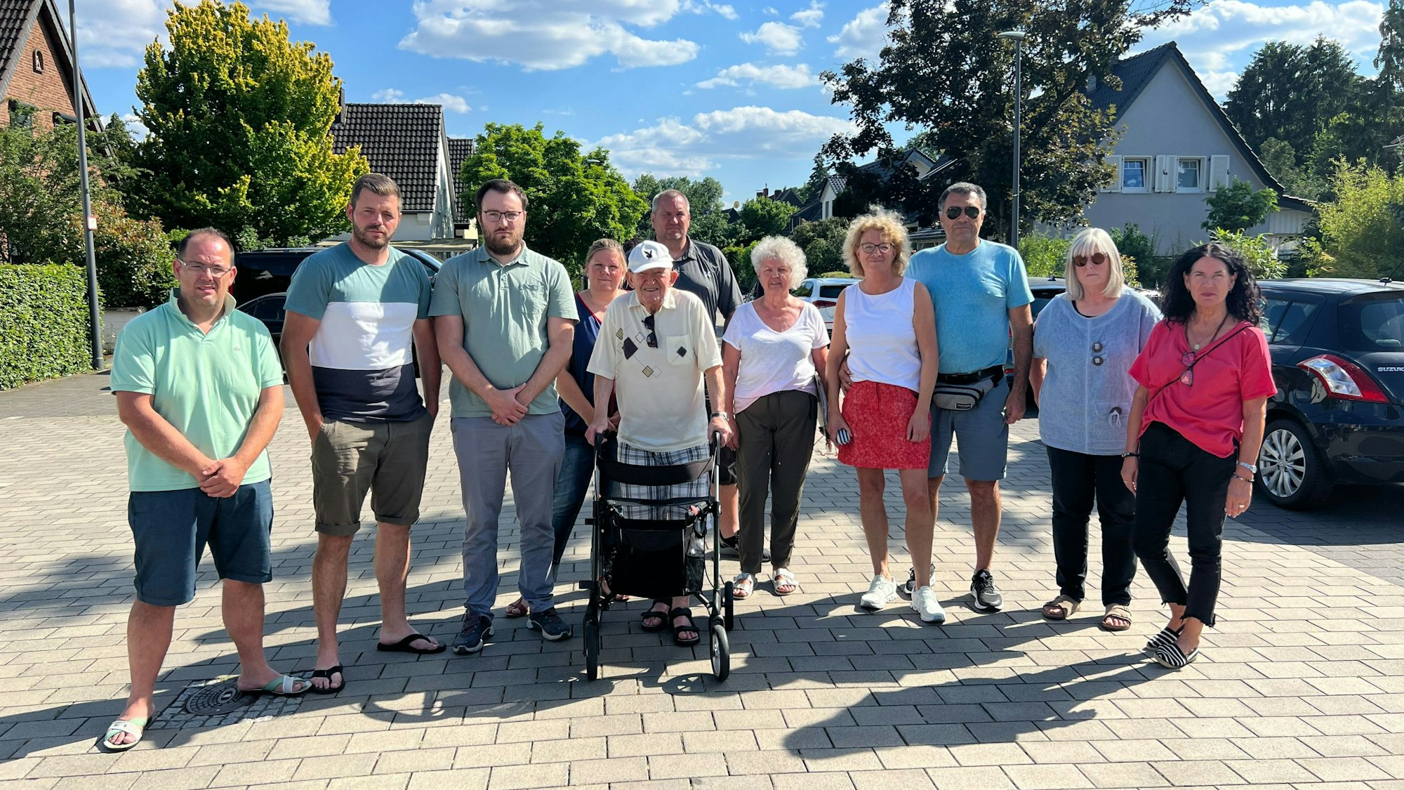 Mehrere Menschen stehen nebeneinander auf einer Straße.