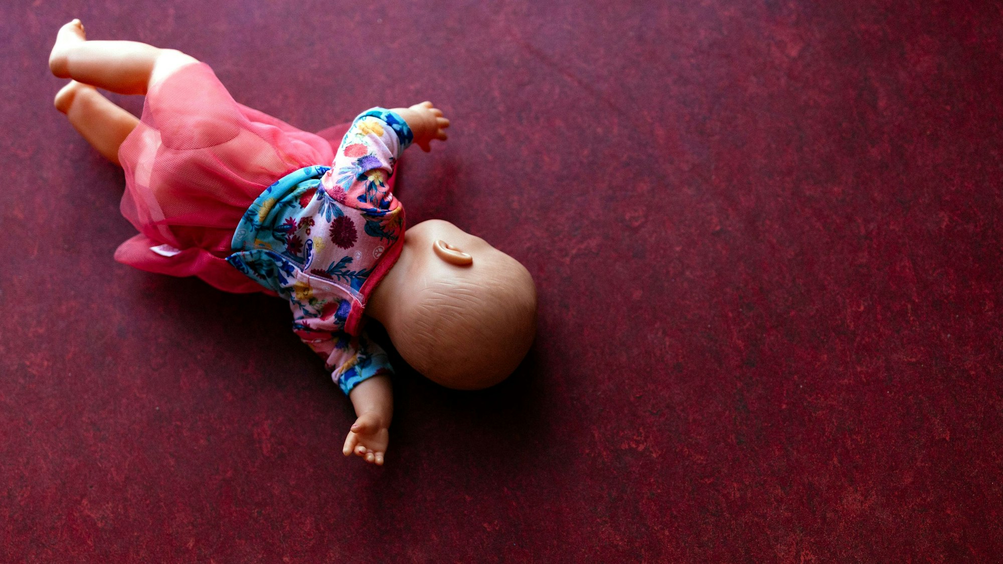 Eine Spielzeugpuppe liegt auf einem PVC-Fußboden.