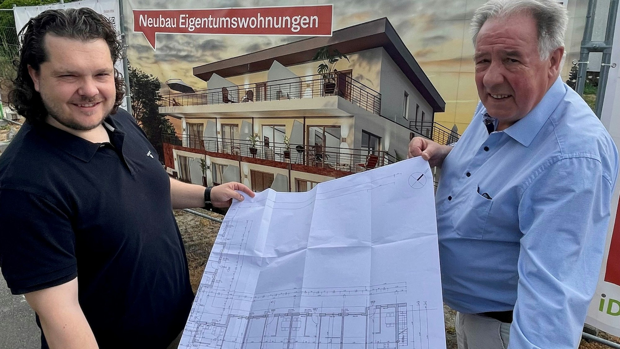 Torben Lohbeck, Stadtplaner bei Idealquadrat Immobilien und Reiner Ostertag, Seniorpartner beim Projektentwickler zeigen den Bauplan vor einem Plakat mit der Visualisierung des Neubaus am Ziegelacker in Liblar.
