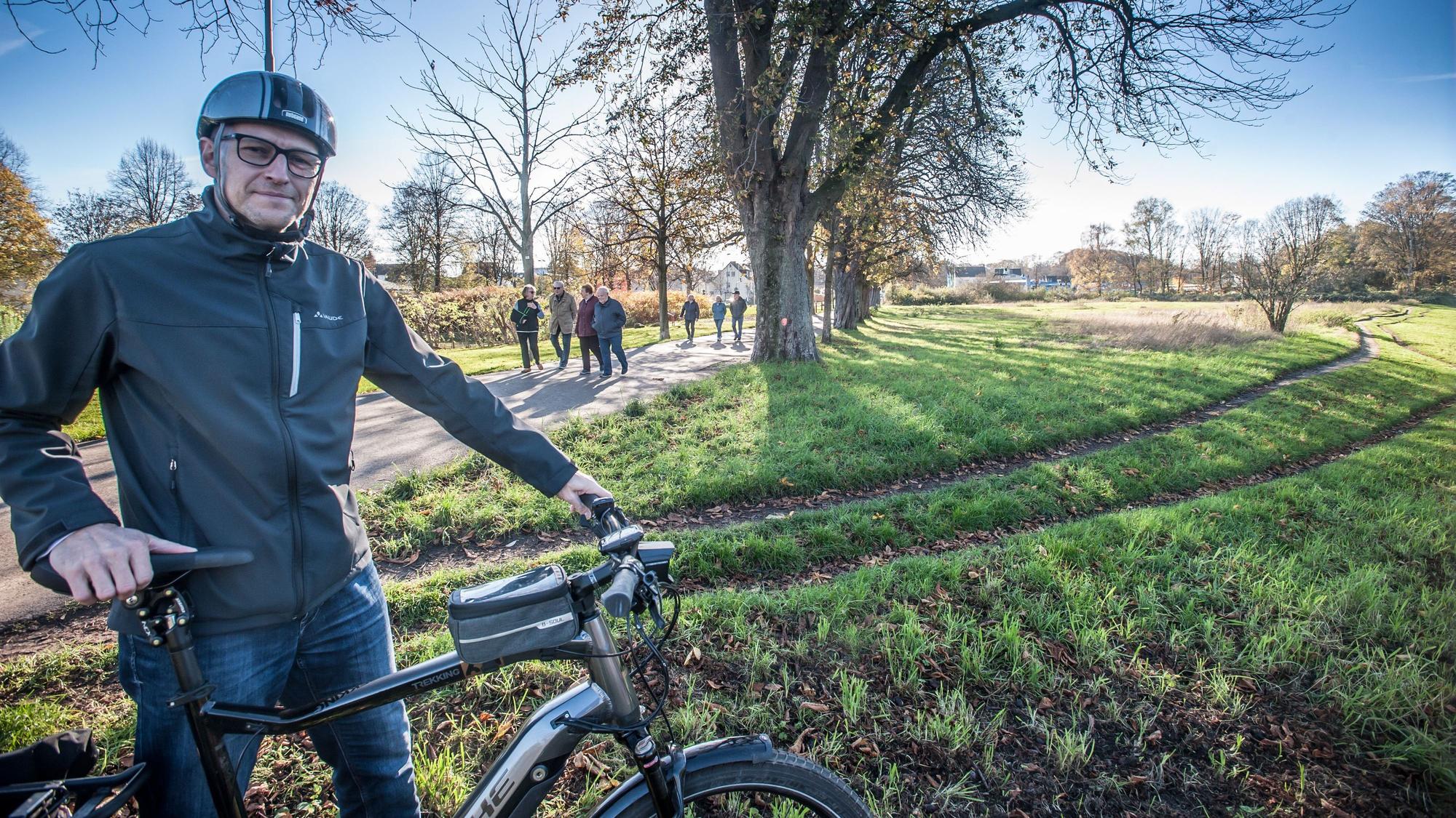 Der Opladener Matthias Itzwerth steht mit seinem Fahrrad an einer Wiese.