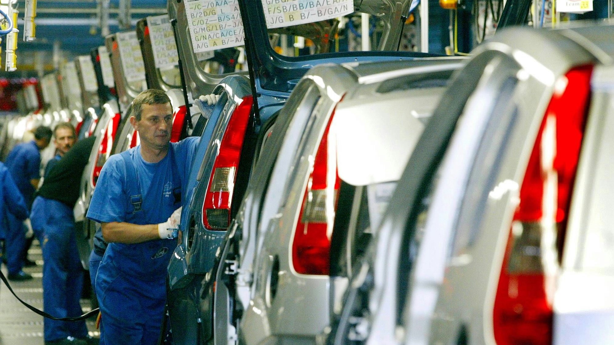 Automonteure einer Fertigungslinie in den Kölner Fordwerken 2002: Ein Mann in blauer Arbeitshose