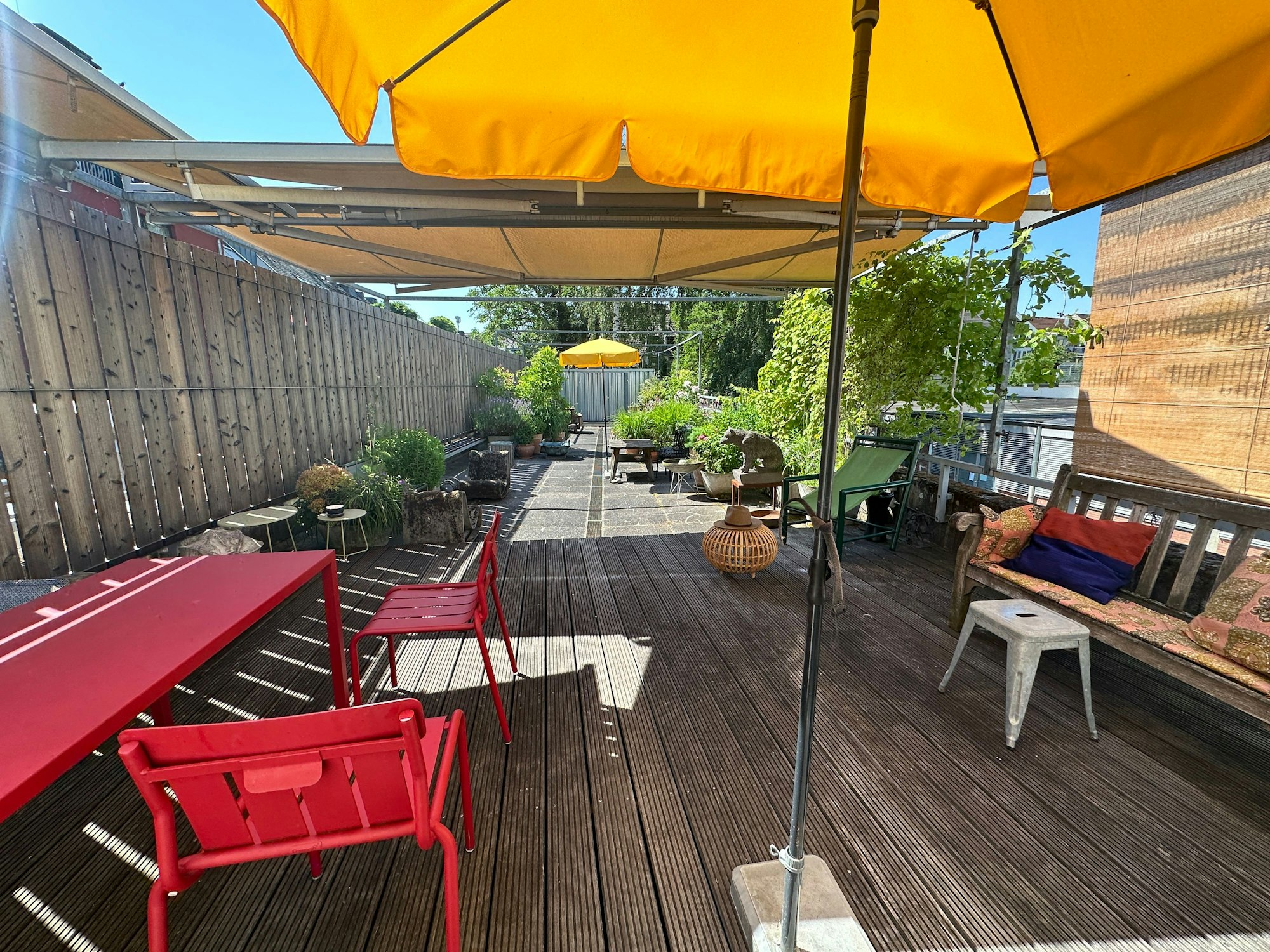 Gelbe Sonnenschirme stehen auf den Holzplanken einer großen rechteckigen Terrasse.