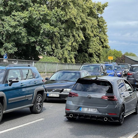 Auf einer Brücke ist ein langer Rückstau, auch die Gegenfahrbahn ist stark befahren.
