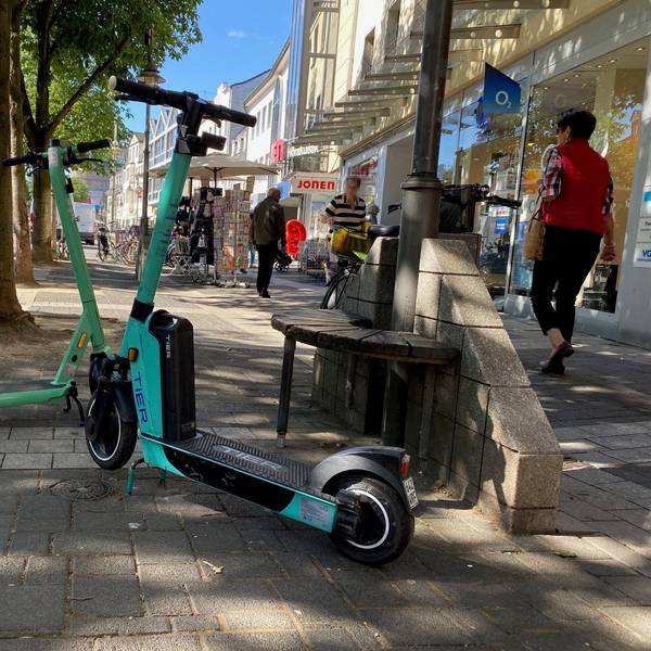 Zwei E-Scooter stehen in der Brühler Fußgängerzone, Passanten umkurven die kleinen Elektroflitzer.