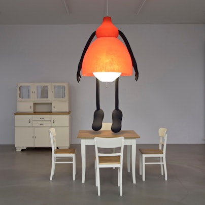 Eine Frau in Lampenform hängt von der Zimmerdecke.