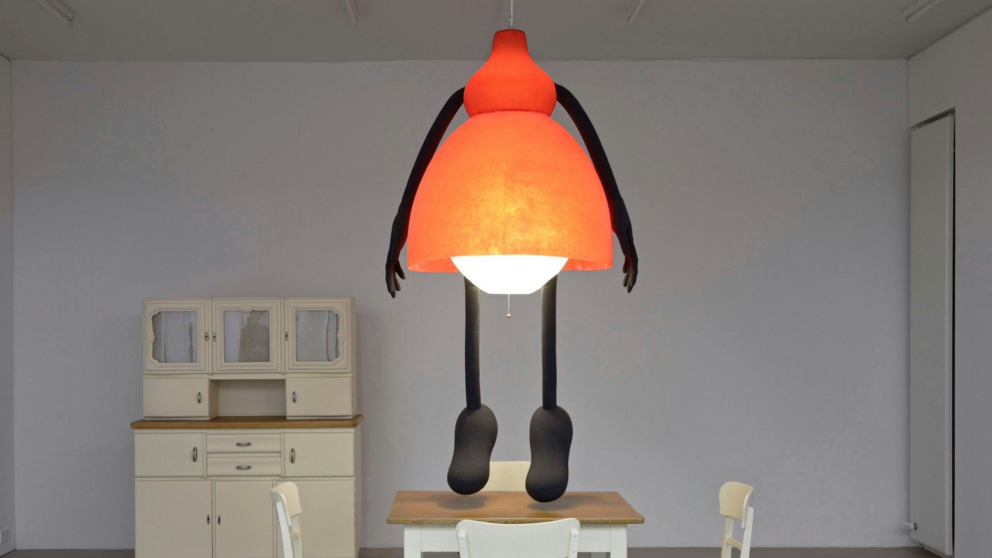 Eine Frau in Lampenform hängt von der Zimmerdecke.