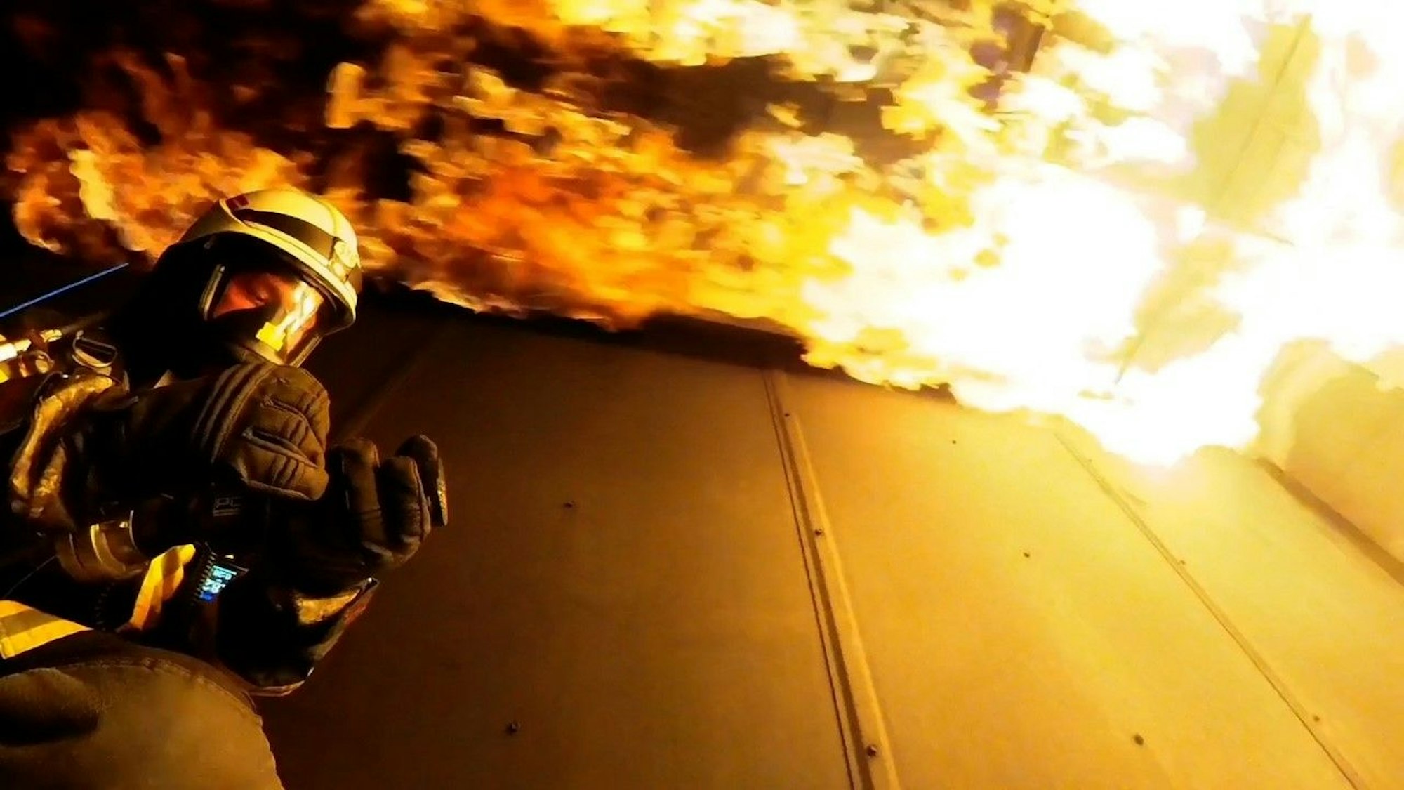 Flammen schlagen im Brandcontainer an der Decke entlang.