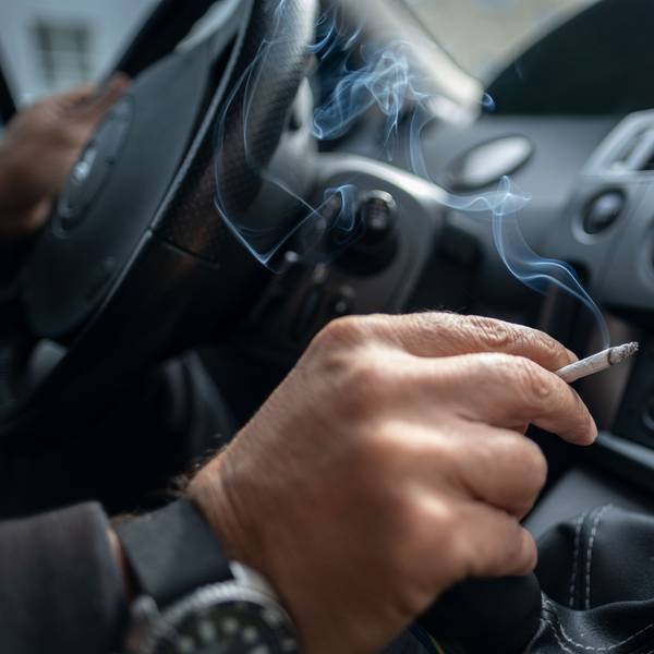 Ein Mann sitzt rauchend am Lenkrad eines Autos. (Symbolbild)